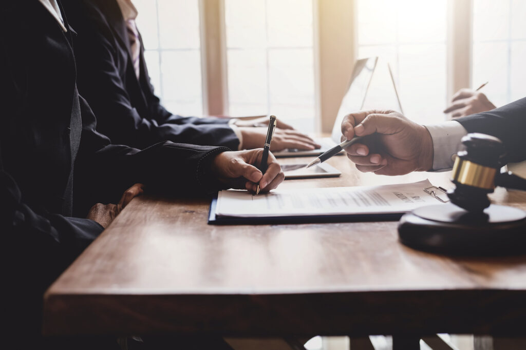 Lawyer and client reviewing and signing legal documents at a desk with a gavel.